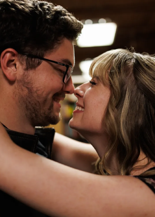 A close-up of two people in an intimate embrace, showcasing their arms and shoulders, with a soft focus background.